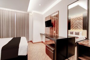 A hotel room with a bed, a desk, a TV, and a large mirror. - Townhouse Oak Near The Park Mall Semarang (Semarang)