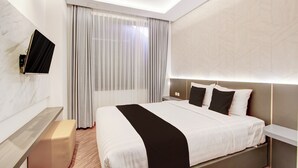 A modern hotel room with a large bed, a flat-screen TV mounted on the wall, and a bedside table. - Townhouse Oak Near The Park Mall Semarang (Semarang)