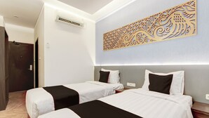 A hotel room with two beds, a decorative wall piece, an air conditioning unit, and a wooden floor. - Townhouse Oak Near The Park Mall Semarang (Semarang)