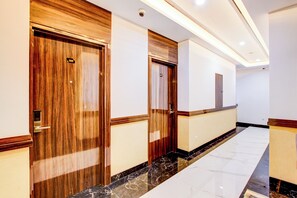 A hallway with wooden doors, marble flooring, and recessed lighting.