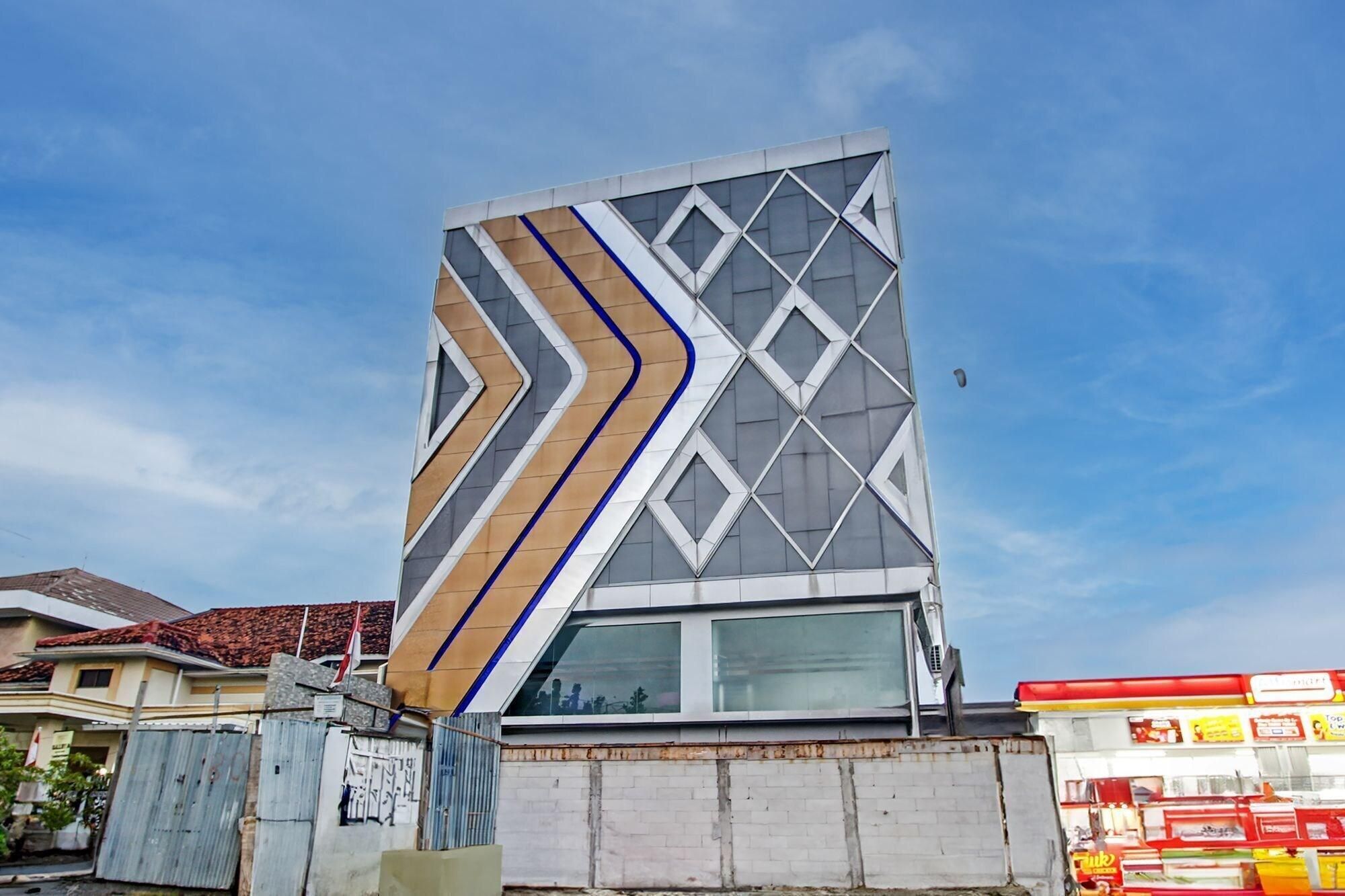 A modern building with a unique angular facade, large windows, and a visible storefront with signage.