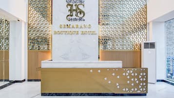A reception desk with a marble top and a gold accent, flanked by decorative panels and a wooden panel wall.