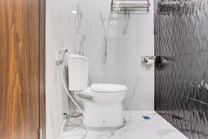 A modern bathroom with a toilet, marble walls, and a wooden door. - Townhouse Oak Near The Park Mall Semarang (Semarang)