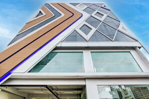 Un edifici modern amb façana geomètrica, grans finestres i una entrada destacada.