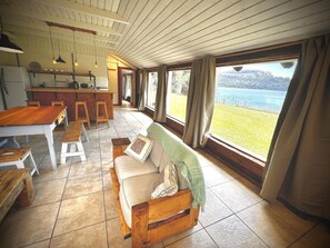 Una cocina amplia con comedor, un banco de madera y un sofá con vista al lago.