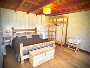 Una cama de madera con cajones, una mesita de noche, una escalera de madera y una silla.