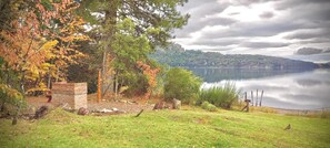 A lakeside view with a grassy area, a stone structure, and a wooden fence. - Apartments Bariloche - Moreno Lake (San Carlos de Bariloche)