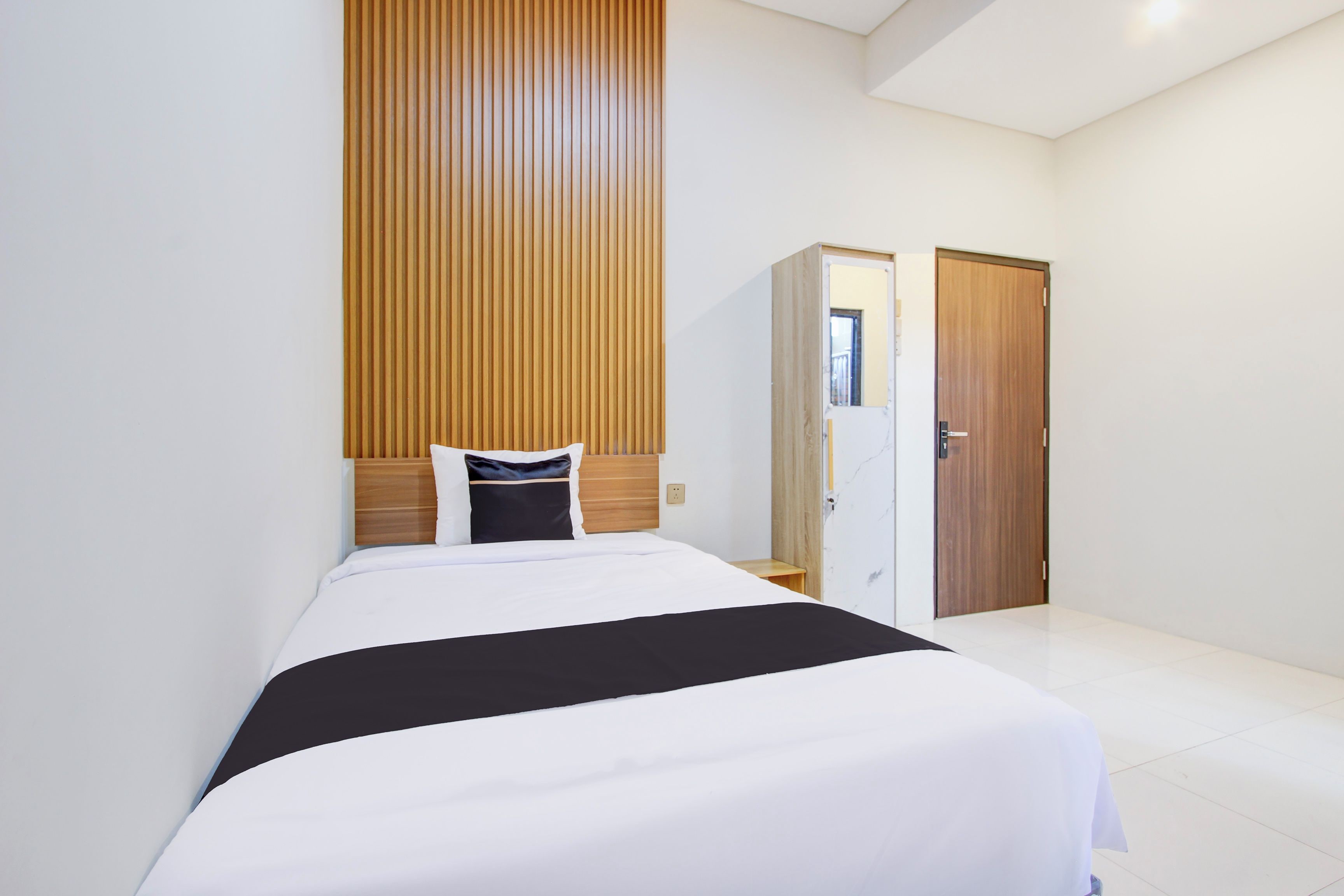 A hotel room with a bed, a wooden headboard, a wardrobe, and a door.