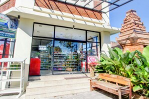 Ein Schaufenster mit Glasfront, eine Bank davor und ein Backsteinhaus im Hintergrund.