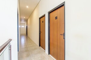 Un pasillo con puertas de madera, cada una con un número, que dan a varias habitaciones.