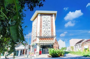 Un edificio con una fachada decorativa llamativa, una entrada amplia y un pequeño jardín delantero.