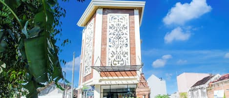 Un edificio con una fachada decorativa llamativa, una entrada amplia y un pequeño jardín delantero.