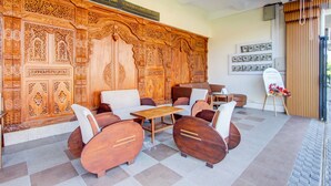 Un hall d’entrée doté d’un grand mur recouvert de panneaux en bois, un espace détente avec des canapés et des fauteuils, une petite table et un présentoir avec des photos.