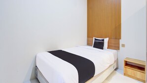 A neatly made bed with a black and white bedspread, a wooden headboard, and a small wooden nightstand beside it. - Collection O Solo Near Univ Muhammadiyah Surakarta (Surakarta)