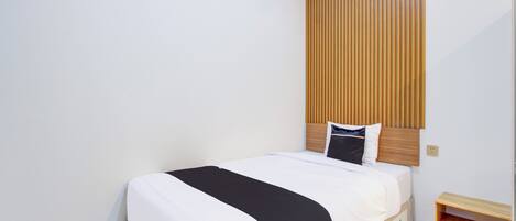 Una cama bien hecha con una colcha blanco y negro, un cabecero de madera y una mesita de noche de madera a su lado.