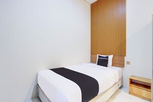 Una cama bien hecha con una colcha blanco y negro, un cabecero de madera y una mesita de noche de madera a su lado.