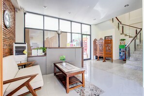 Ein modernes Interieur mit einer Couch, einem Holztisch mit Pflanze, einer Wanduhr und einer Treppe.