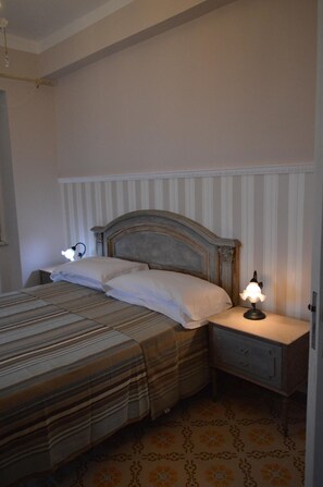 A bedroom with a bed, bedside lamps, a nightstand, and a patterned floor. - B B Al Golfo (Salerno)
