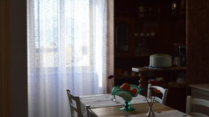 A dining area with a table set for two, a hanging light fixture, and a window with sheer curtains. - B B Al Golfo (Salerno)