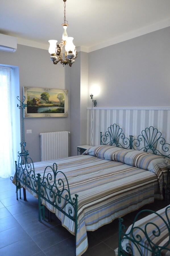 A bedroom with a bed, a radiator, a painting, and a chandelier. - B B Al Golfo (Salerno)