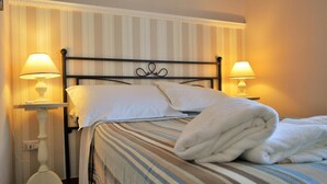 A hotel room with a bed, two bedside lamps, and a striped bedspread. - B B Al Golfo (Salerno)