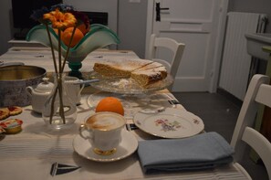 A dining table with a cake, a teapot, a cup of coffee, and a vase with flowers. - B B Al Golfo (Salerno)