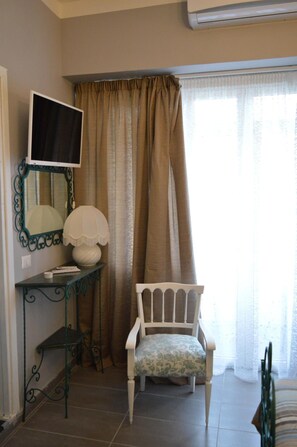 A room with a bed, a chair, a desk with a lamp, a television, and a window with curtains. - B B Al Golfo (Salerno)