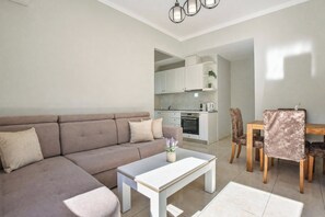 Ein modernes Wohnzimmer mit Sofa, Couchtisch und einem Essbereich mit Stühlen und Tisch.