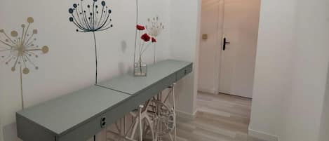 A hallway with a grey console table, white walls, and a door at the end.