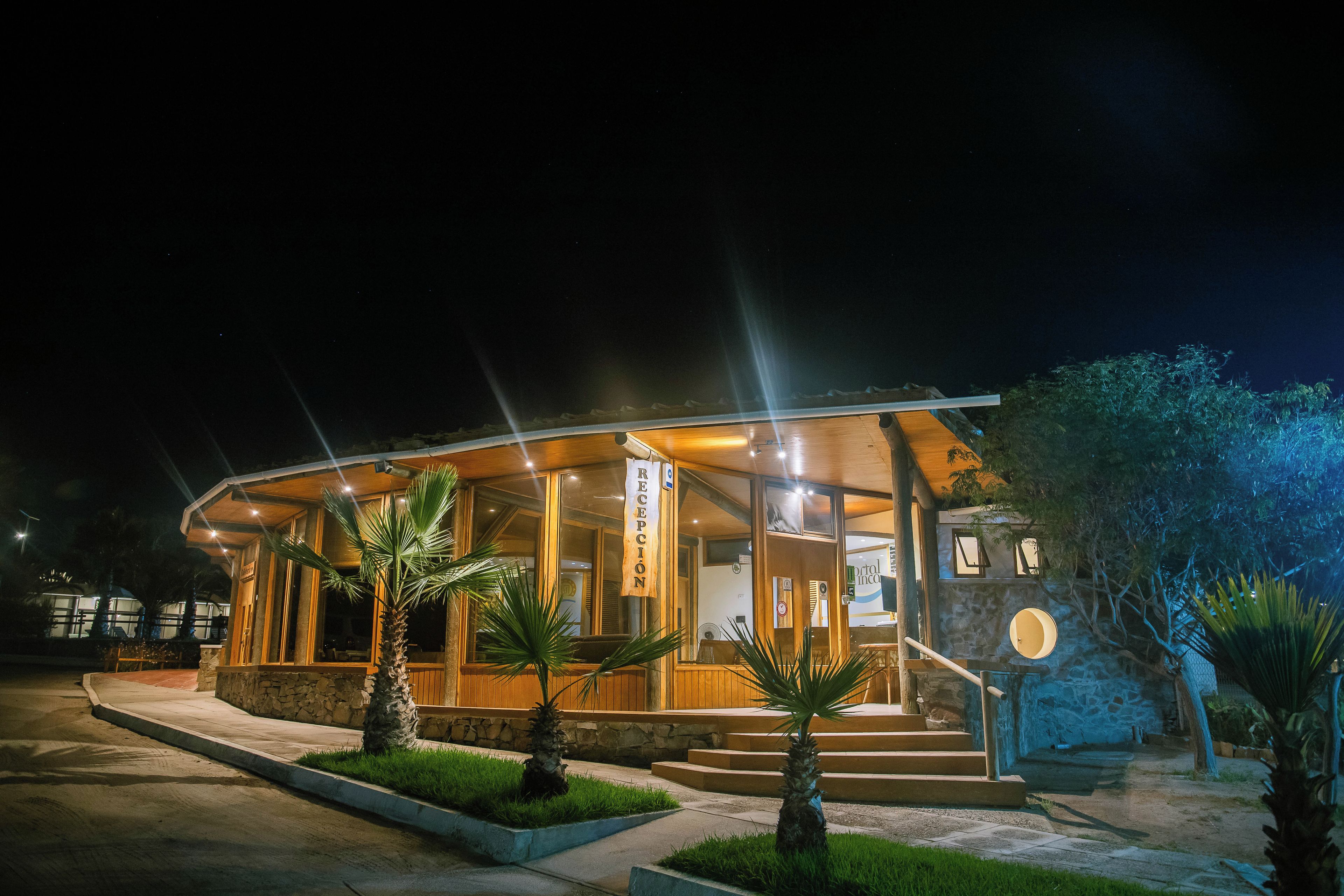 A hotel reception with a stone facade, wooden exterior, and palm trees in the foreground.