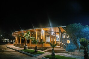 A hotel reception with a stone facade, wooden exterior, and palm trees in the foreground. - Hotel Y Cabañas Portal Del Inca (Caldera)
