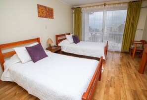 A hotel room with two wooden beds, a nightstand, a chair, and a view through a large window. - Hotel Y Cabañas Portal Del Inca (Caldera)