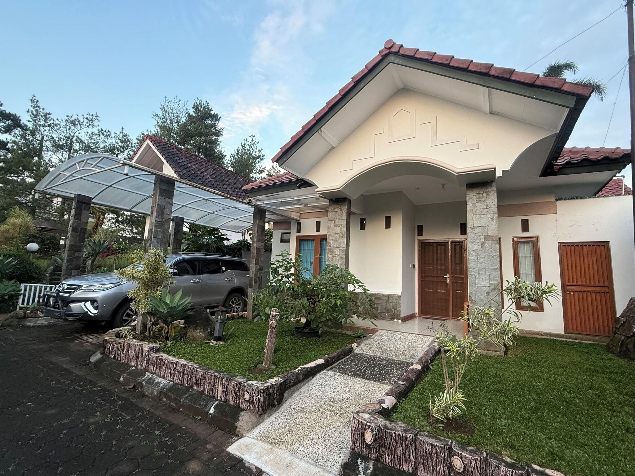 A two-story house with a covered patio, a car parked in the driveway, and a well-maintained lawn.