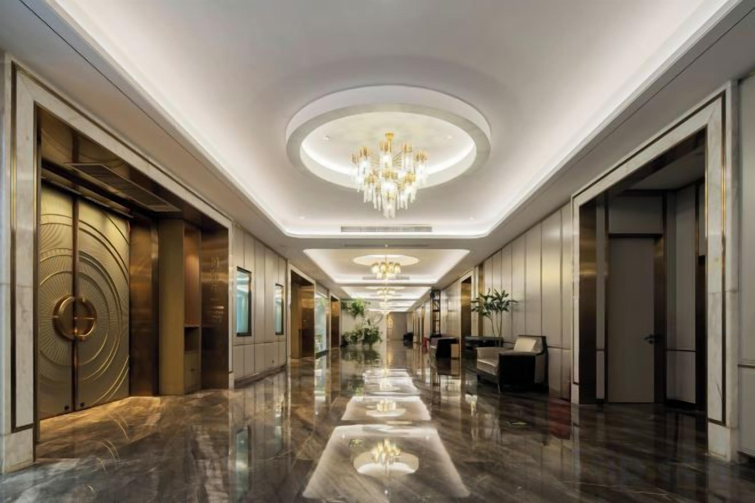 A hotel corridor with a chandelier, polished floors, and doors on both sides.