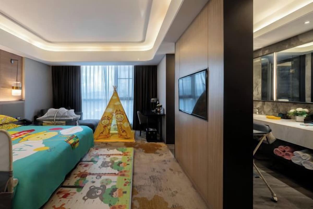 Habitación de hotel con cama, escritorio, silla, televisor y baño.