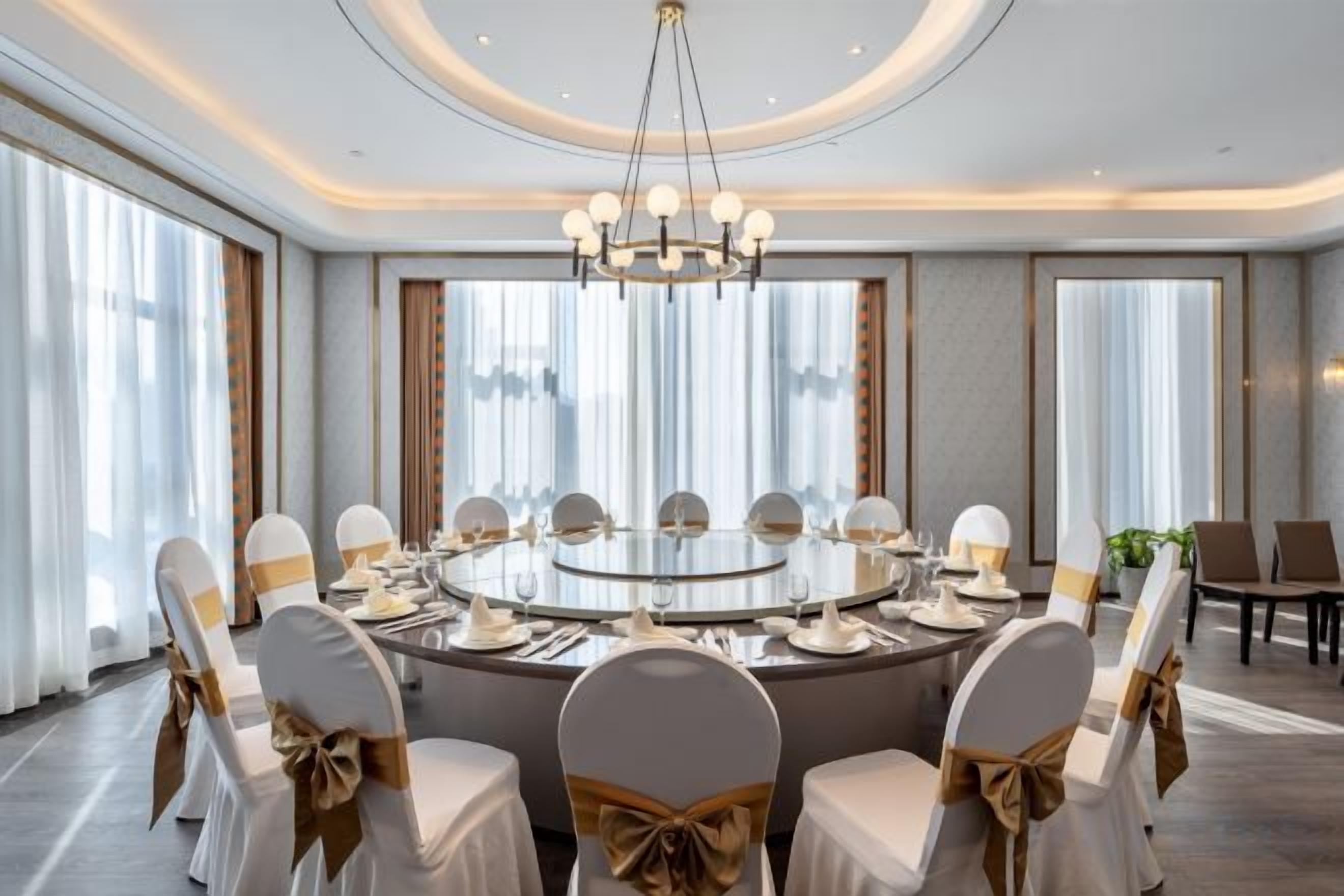 A conference room with a round table, chairs, and a chandelier.