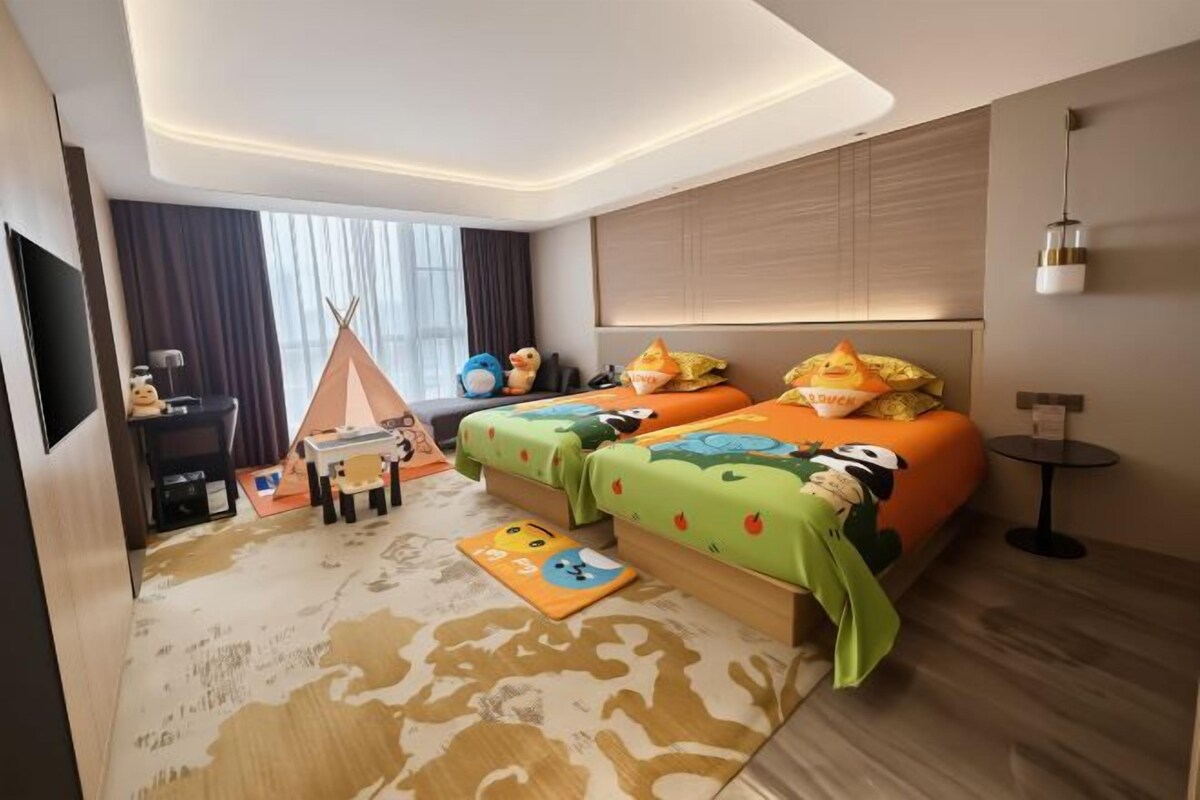 Habitación de hotel con dos camas, un escritorio, una silla, una mesita y una tienda de campaña.