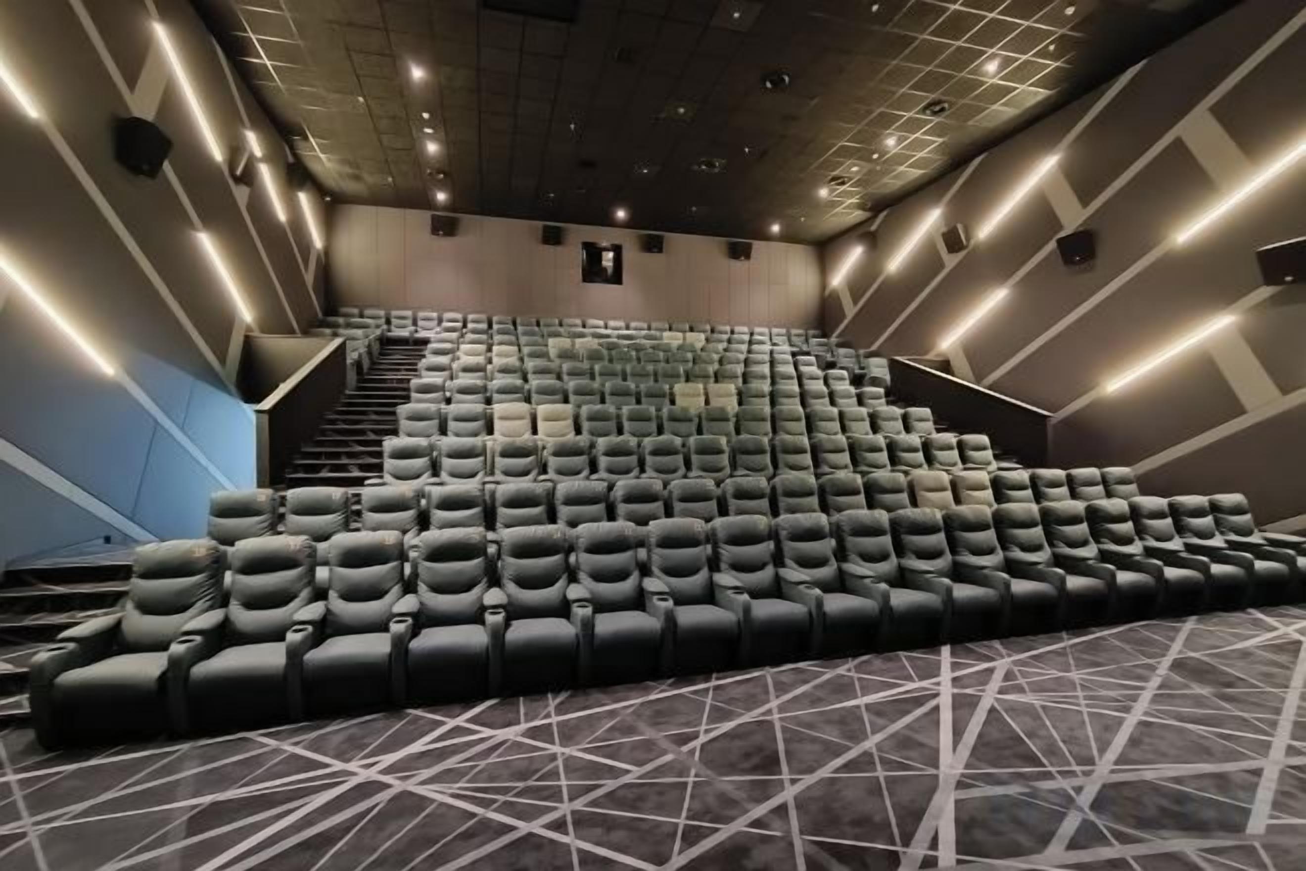 A theater with rows of seats, a staircase, and a patterned carpet.
