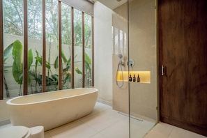 Ein modernes Badezimmer mit freistehender Badewanne, einer in Glas eingefassten Dusche und einer Holztür.