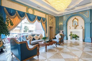 A hotel lobby with a chandelier, blue and gold decor, a fireplace, and a seating area. - Youjia Traders Hotel (Pengzhou Longxing Temple) (Chengdu)