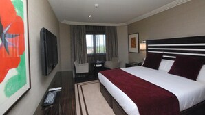 Een hotelkamer met een groot bed, een flatscreen televisie, een bureau en een stoel.