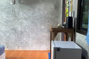 Una habitación con refrigerador, una mesa de madera con cafetera y ventana con vista a follaje.