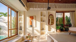 A modern room with a large window, a sofa, a coffee table, and a bed. - Aozora Villas Uluwatu (Uluwatu)