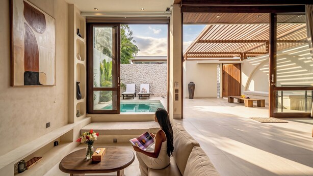 A modern interior with a pool, a sofa, and a table with flowers. - Aozora Villas Uluwatu (Uluwatu)