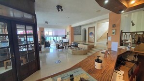 Un vestíbulo de hotel con una recepción, zona de estar, escalera y vistas al comedor.