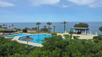 Una piscina con vista al mar, rodeada de palmeras y vegetación.