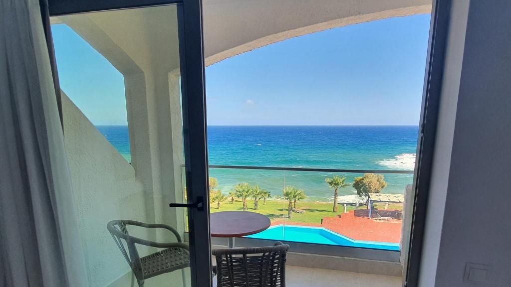 Uma varanda com vista para o mar, uma mesa pequena e uma cadeira.