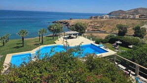 Una piscina con vistas al mar, una zona ajardinada y un edificio al fondo.