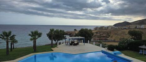 A swimming pool with a view of the sea and a building in the background.