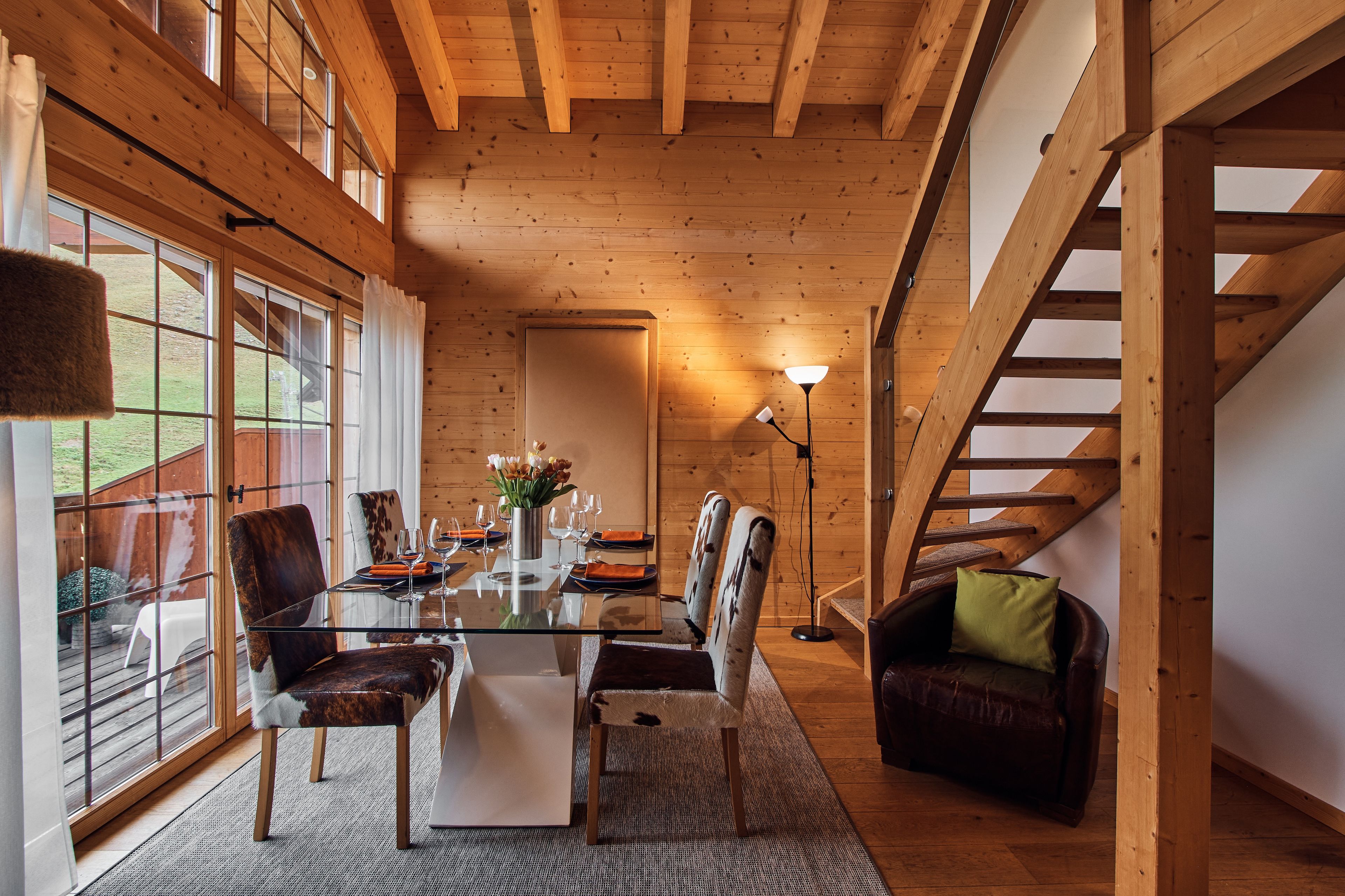 Un intérieur en bois comprenant une table à manger, des chaises, un canapé et un escalier.